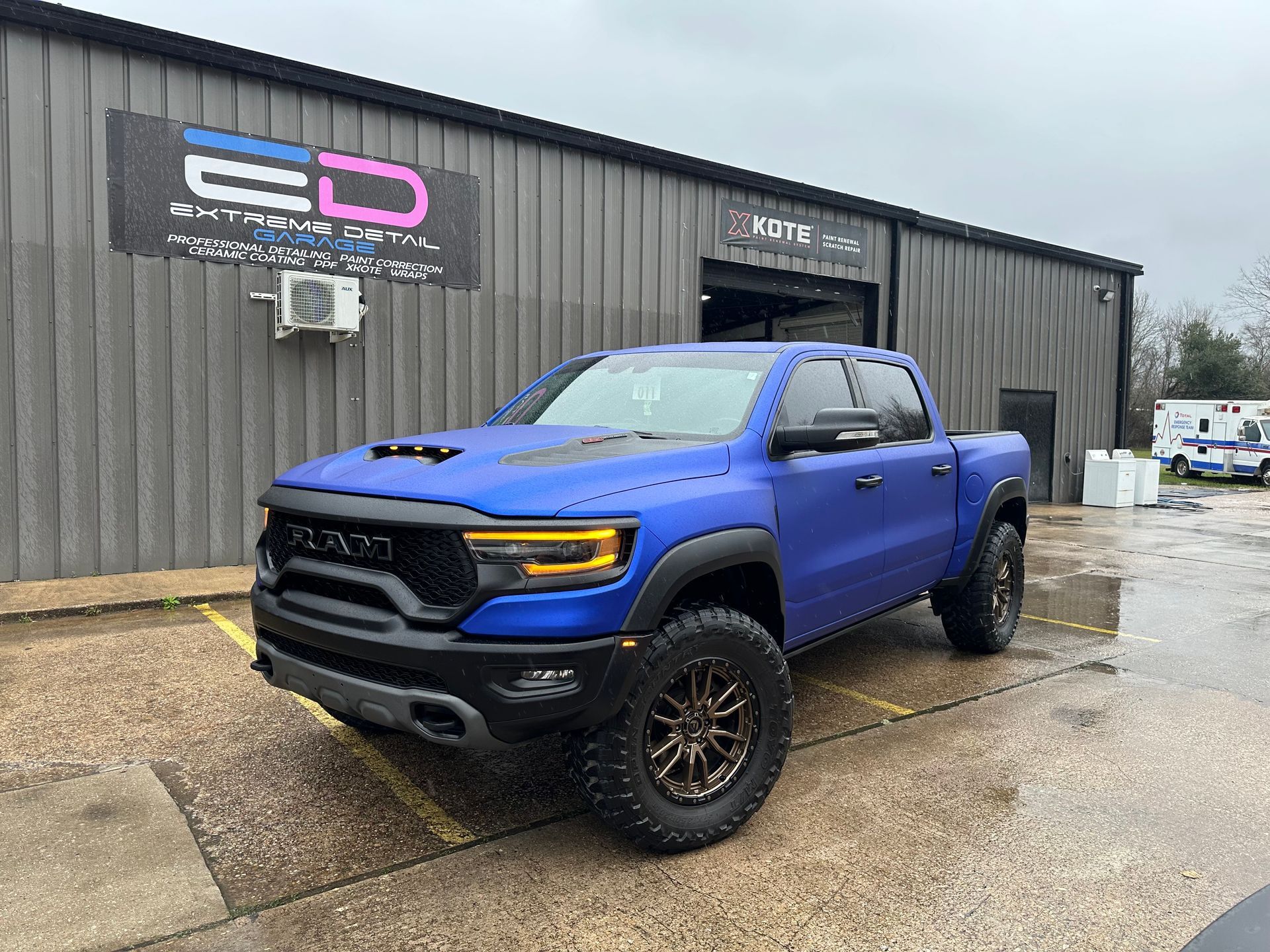 A blue ram truck is parked in front of a building.