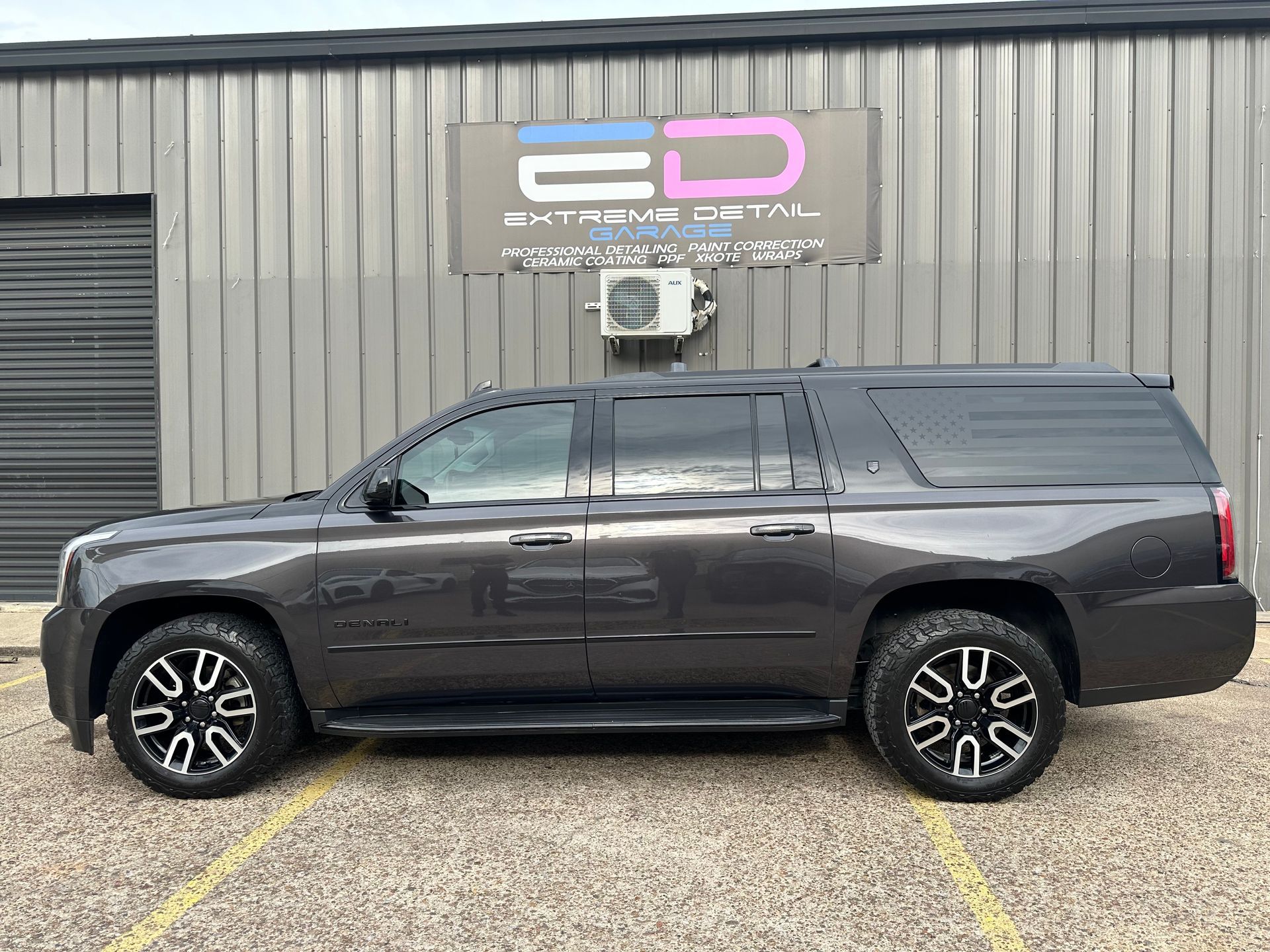 A gray suv is parked in a parking lot in front of a building.