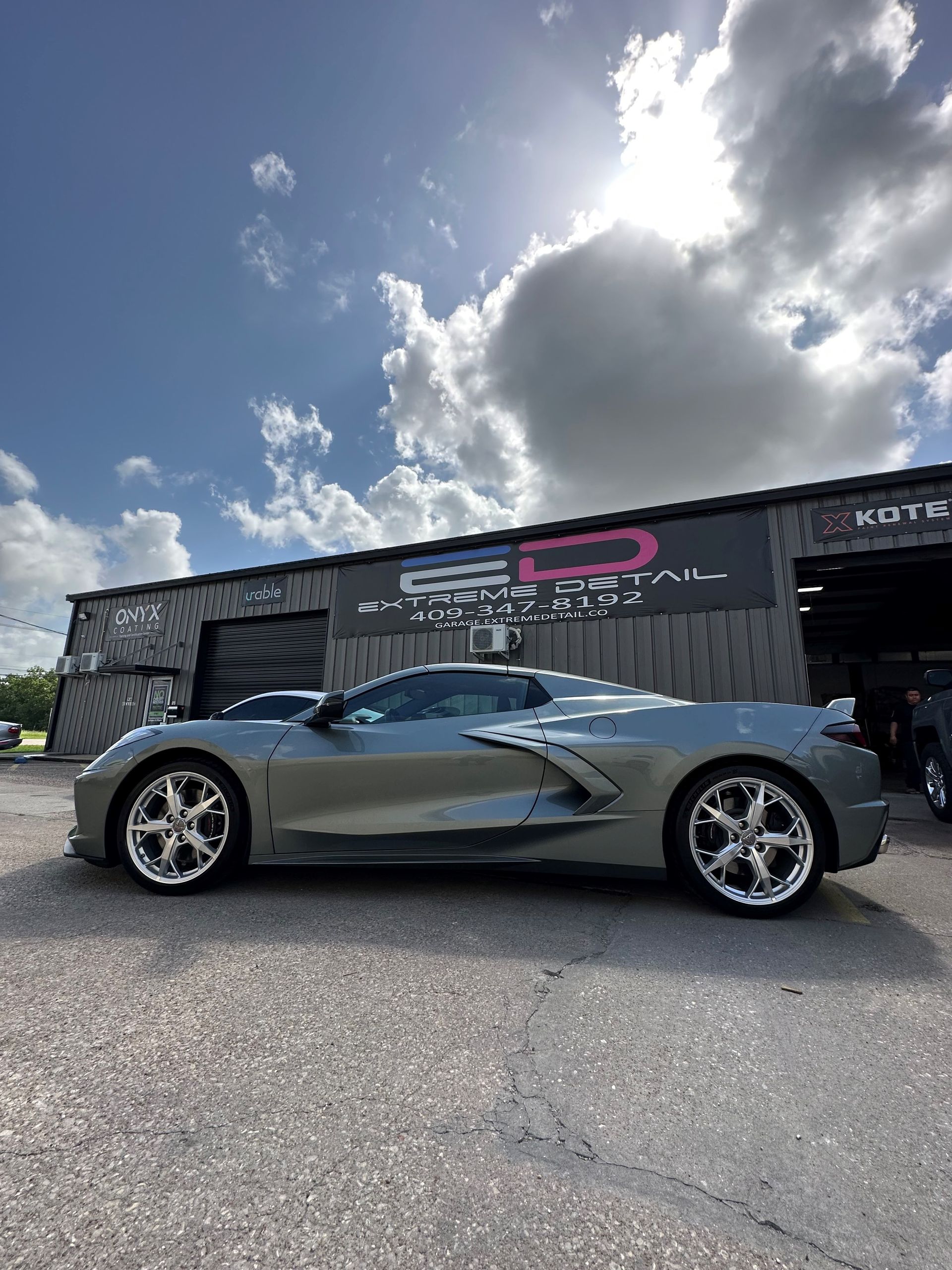 A silver sports car is parked in front of a building.