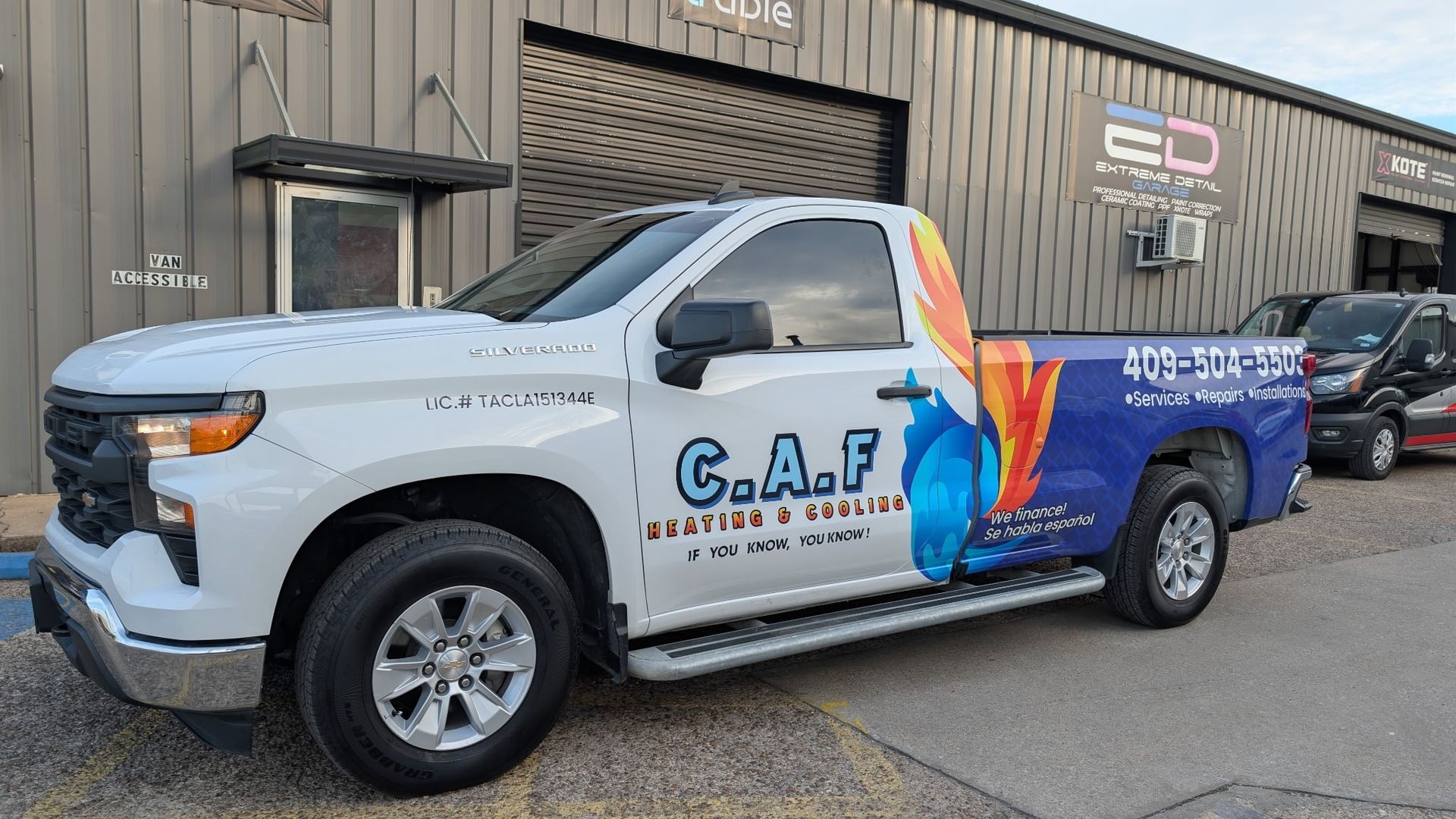 White Chevy pickup truck with company logo parked outside a building.