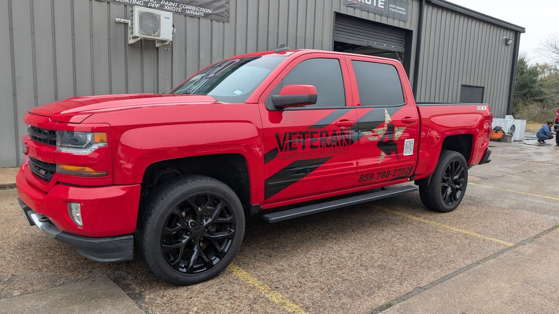 Red Chevy pickup truck with black wheels and a decal on the side.
