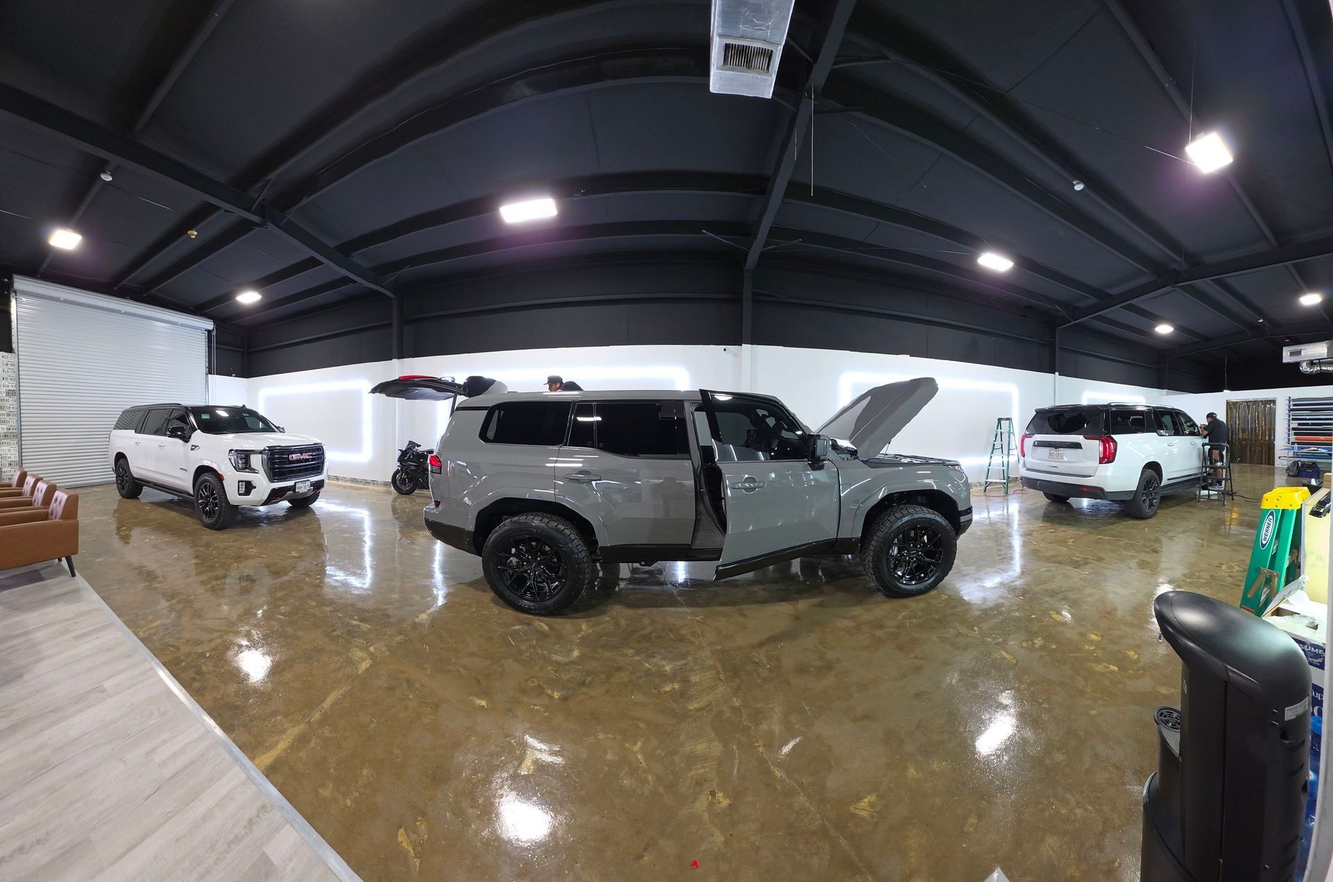 Three SUVs in a glossy indoor garage; a gray truck with doors open in the center.