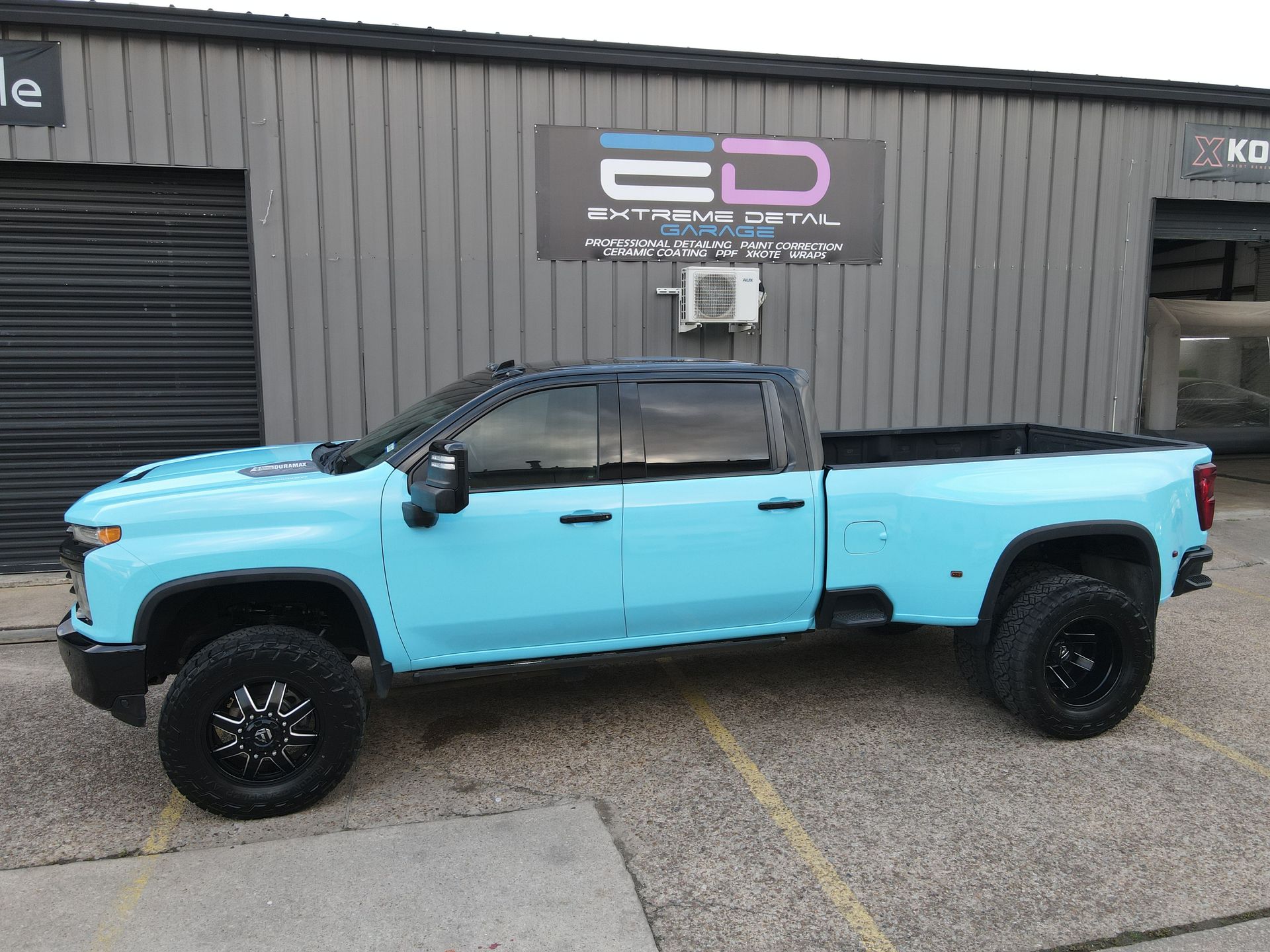 A blue truck is parked in front of a building.