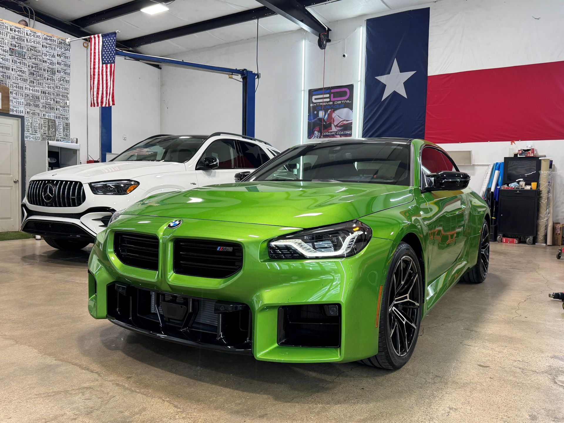 A green bmw m4 is parked in a garage next to a white car.