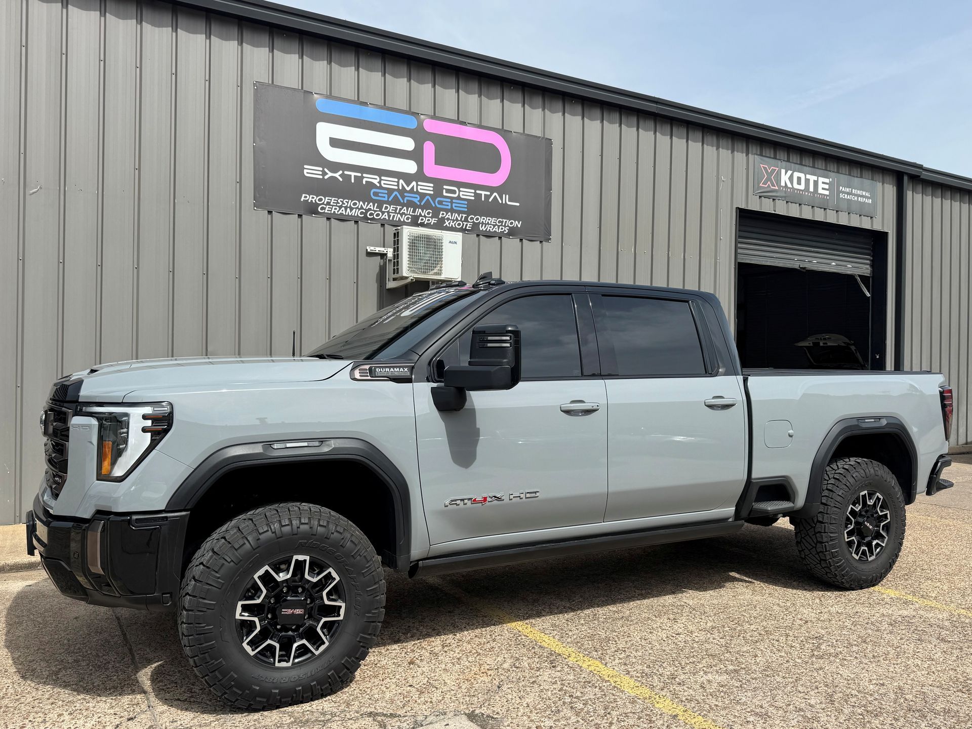 A gray truck is parked in front of a building.