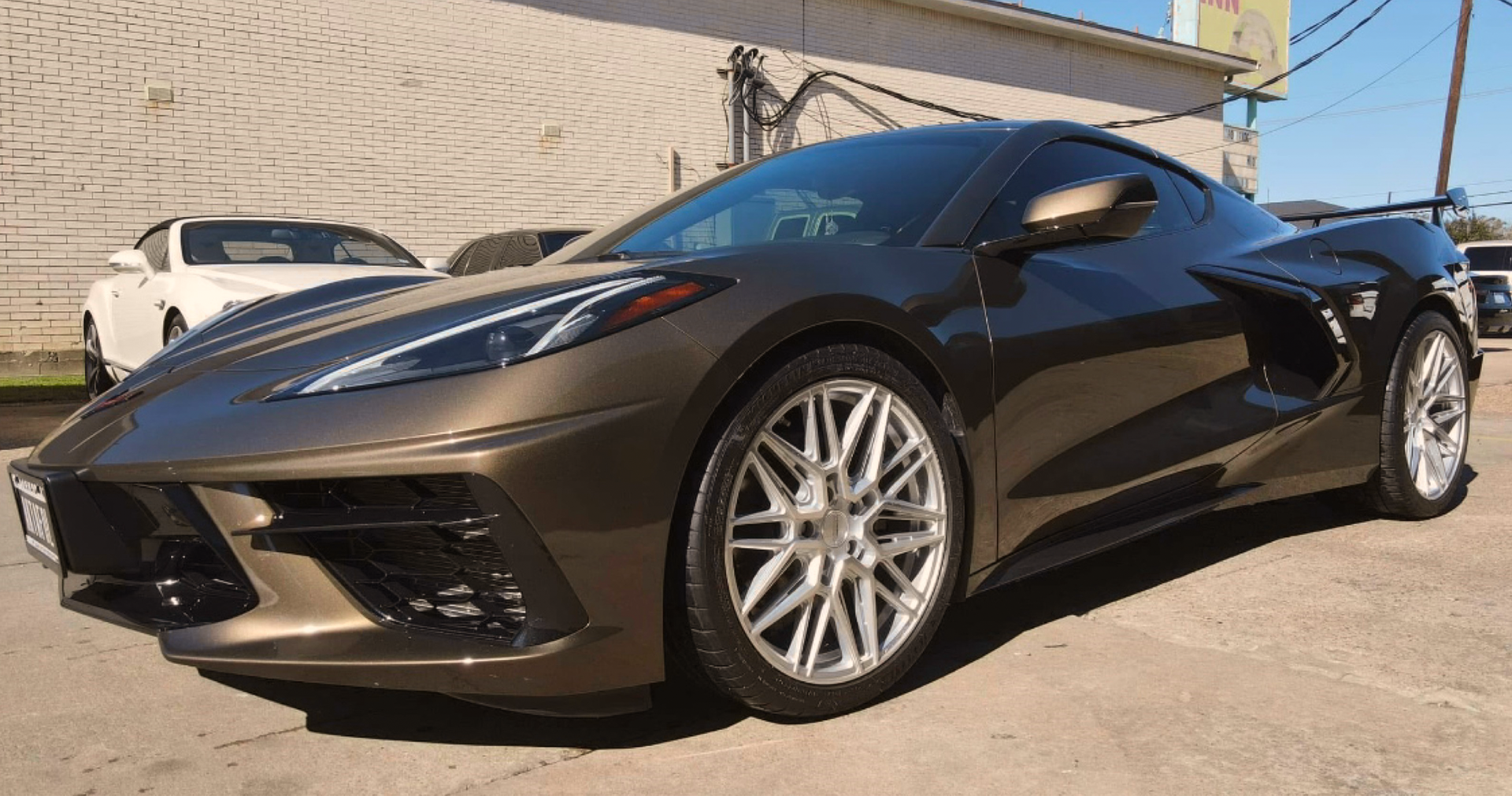 A black sports car is parked in a parking lot in front of a building.