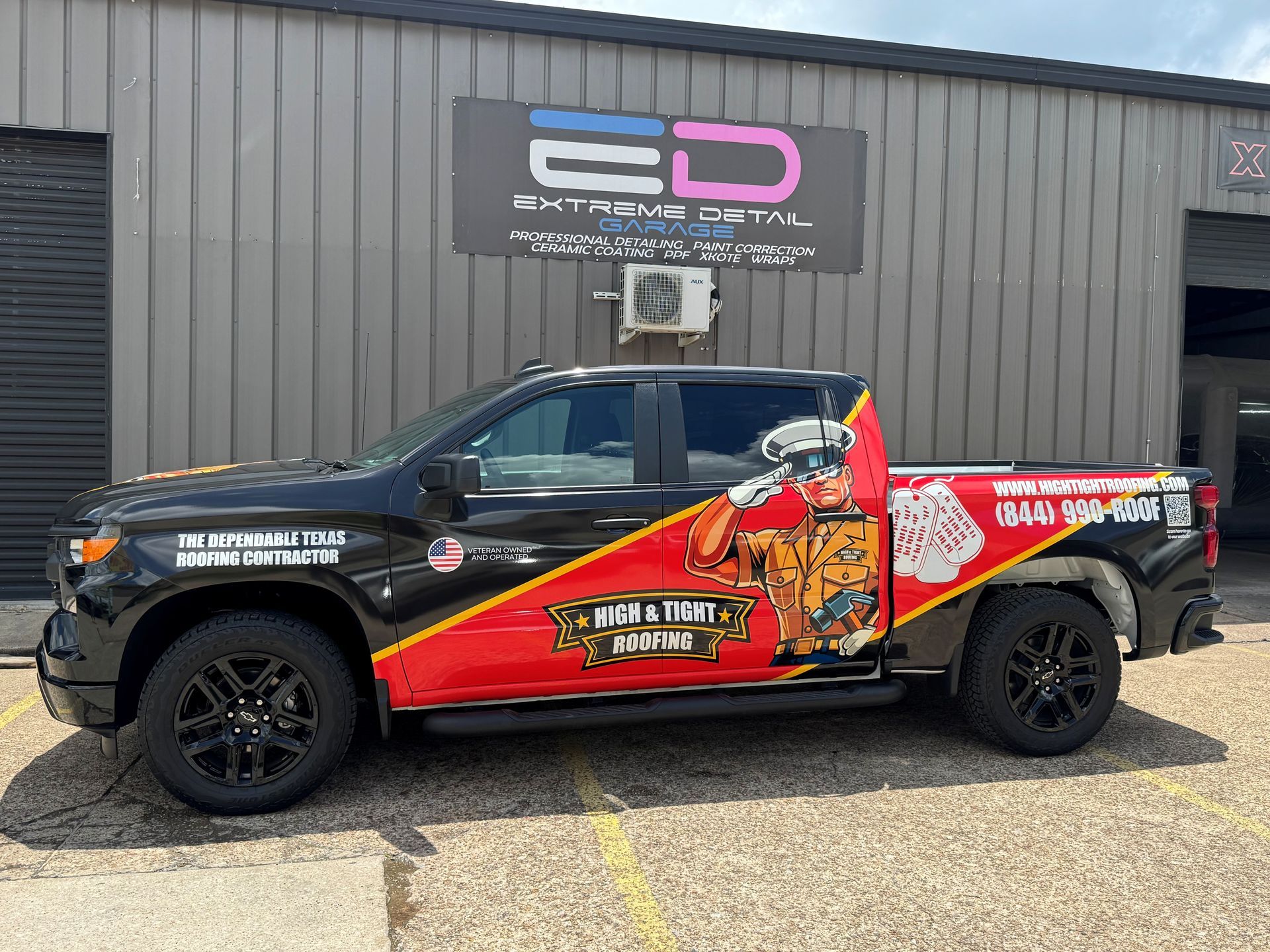 A black and red truck is parked in front of a building.