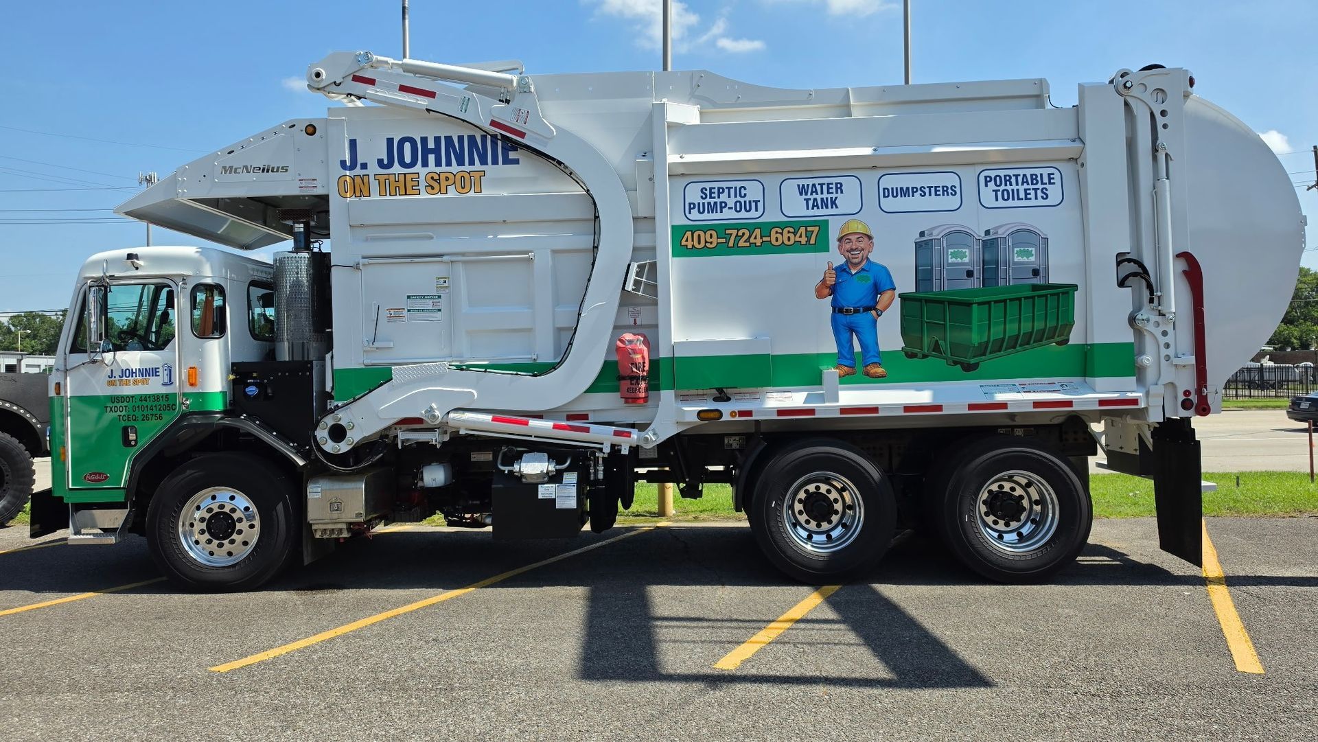 White-and-green utility truck parked in a lot, with a worker standing on the side step under a clear blue sky.