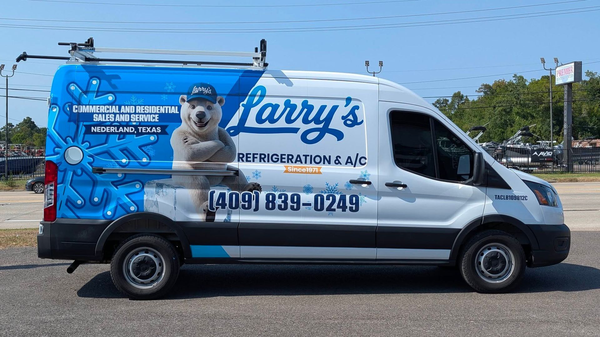 White and blue Larry’s Pest Control van with a bear mascot parked outdoors under a clear sky