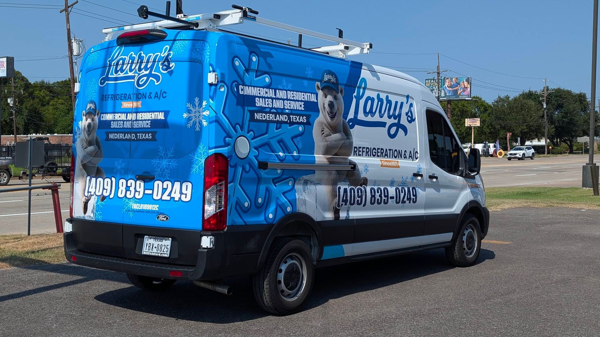 Blue pet grooming van with dog graphics parked outdoors, showing phone numbers and large business lettering on the side