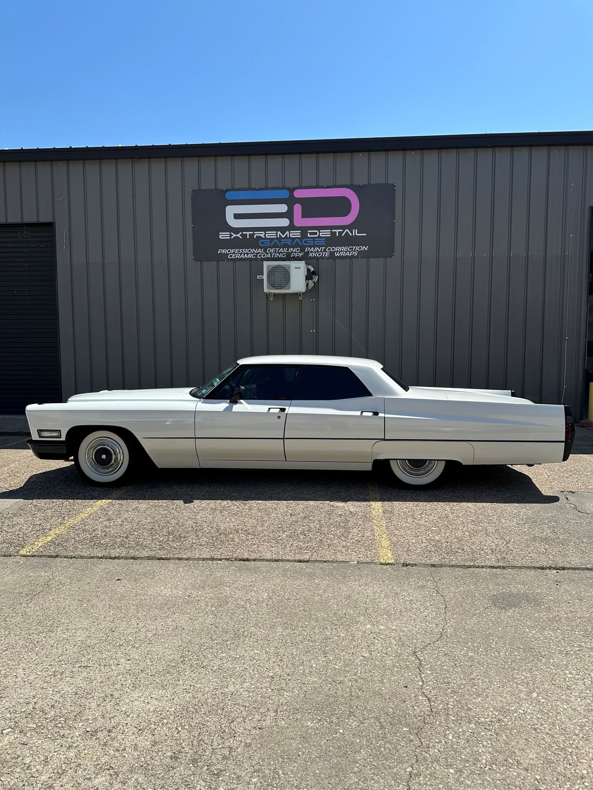 A white car is parked in front of a building.