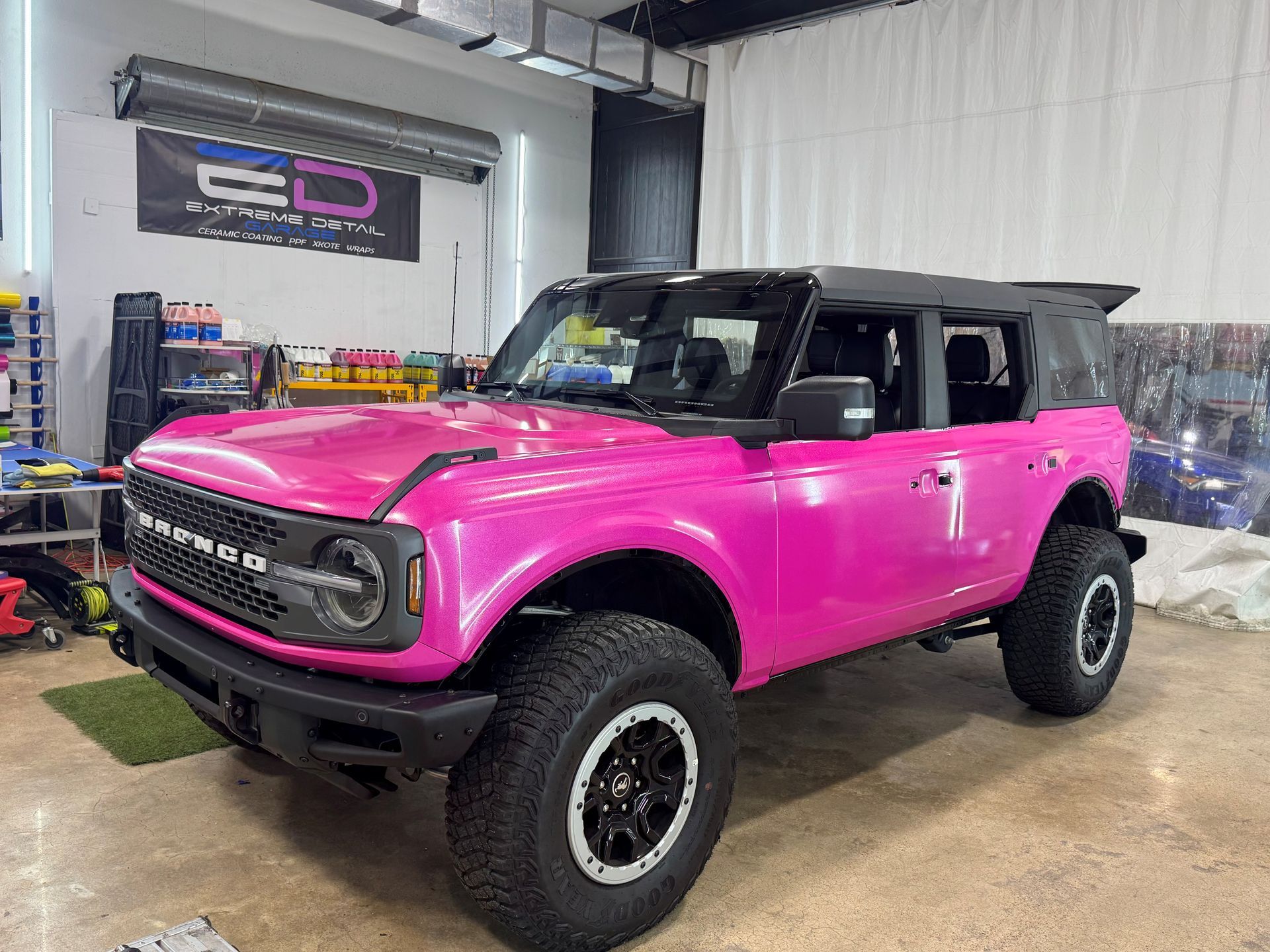 A pink ford bronco is parked in a garage.