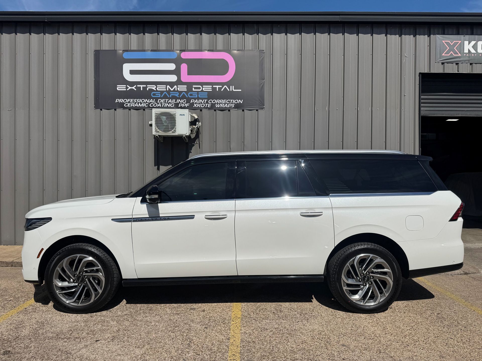 A white suv is parked in front of a building.
