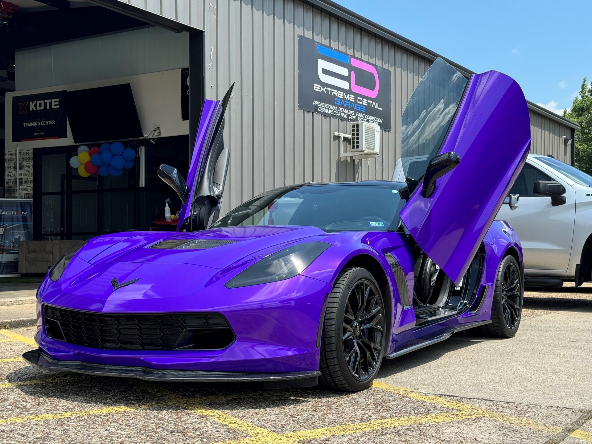 A purple sports car is parked in front of a building with its doors open.
