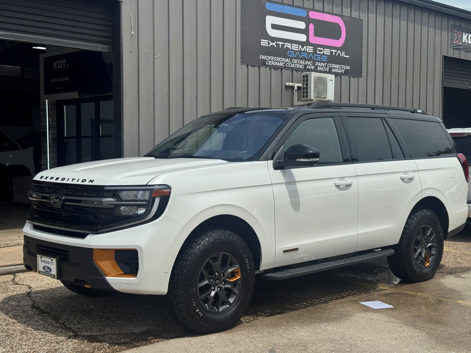 A white ford expedition is parked in front of a building.