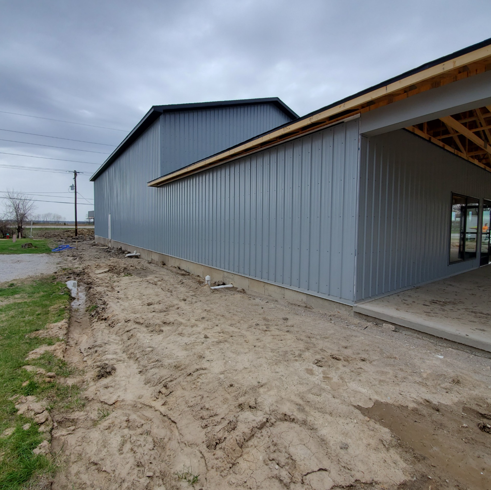 A large building is being built in the middle of a dirt field.