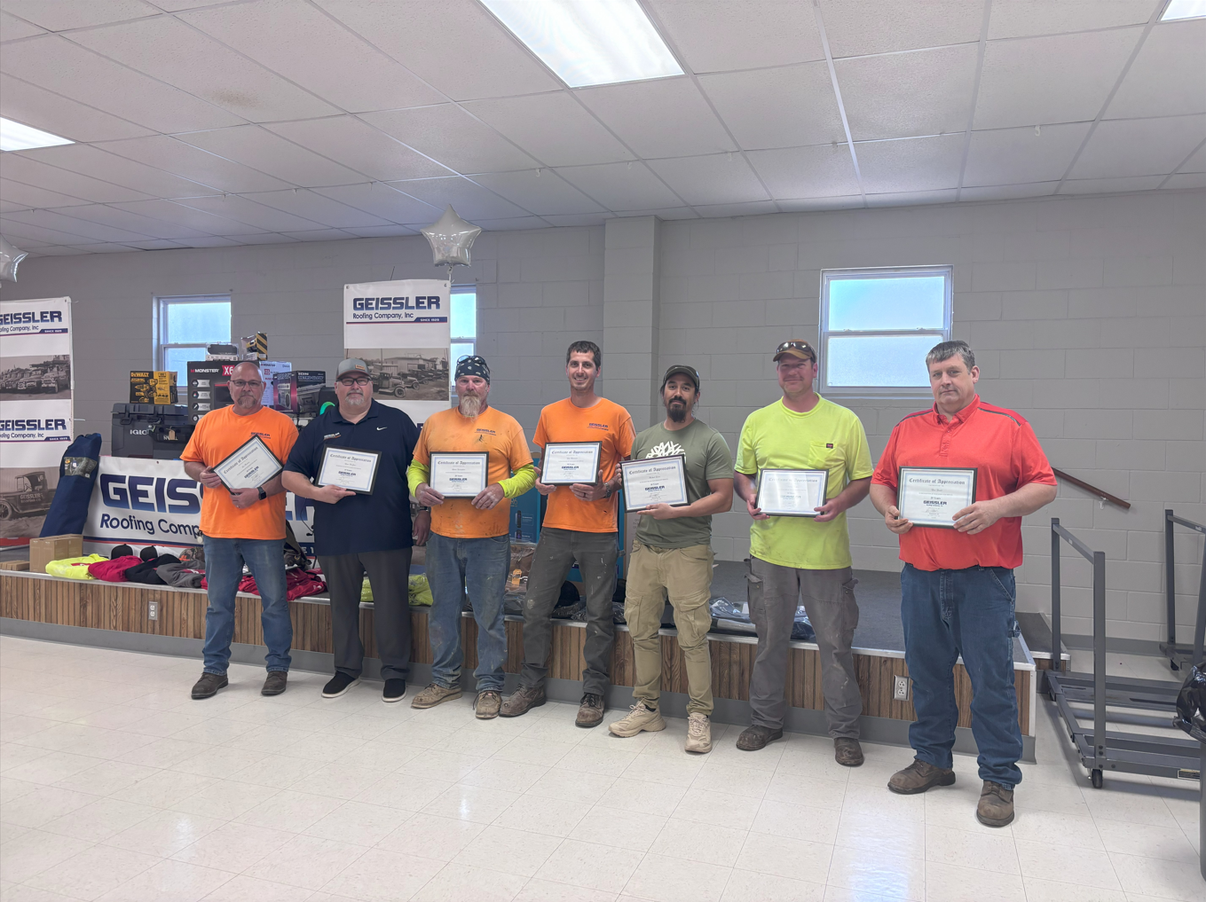 A group of men are standing in a room holding certificates.