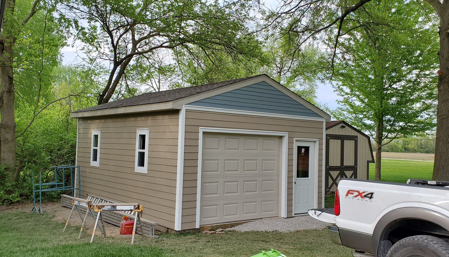 A truck is parked in front of a garage with a blue roof.