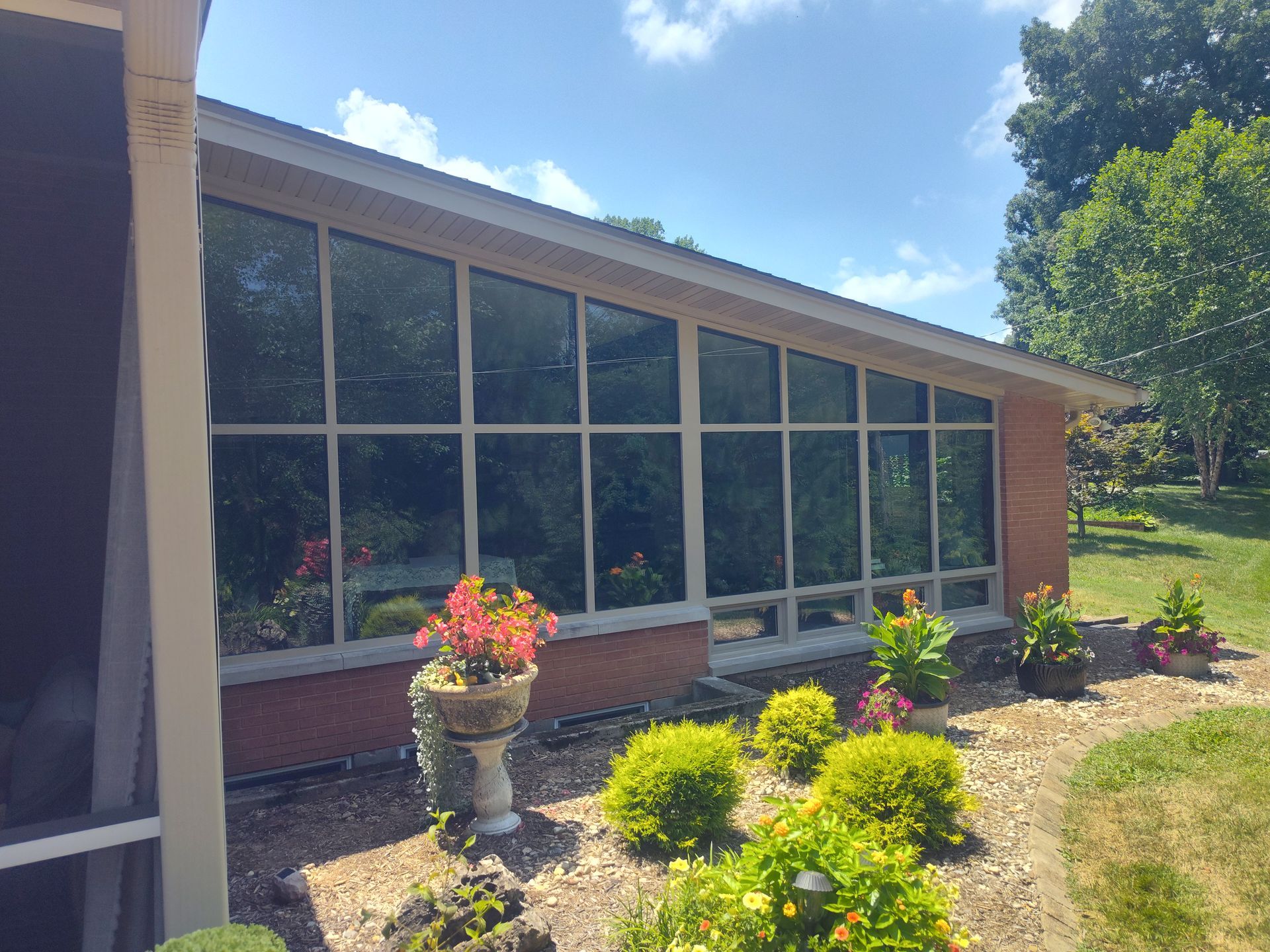 Brick building with large windows, lush landscaping, and blue sky.