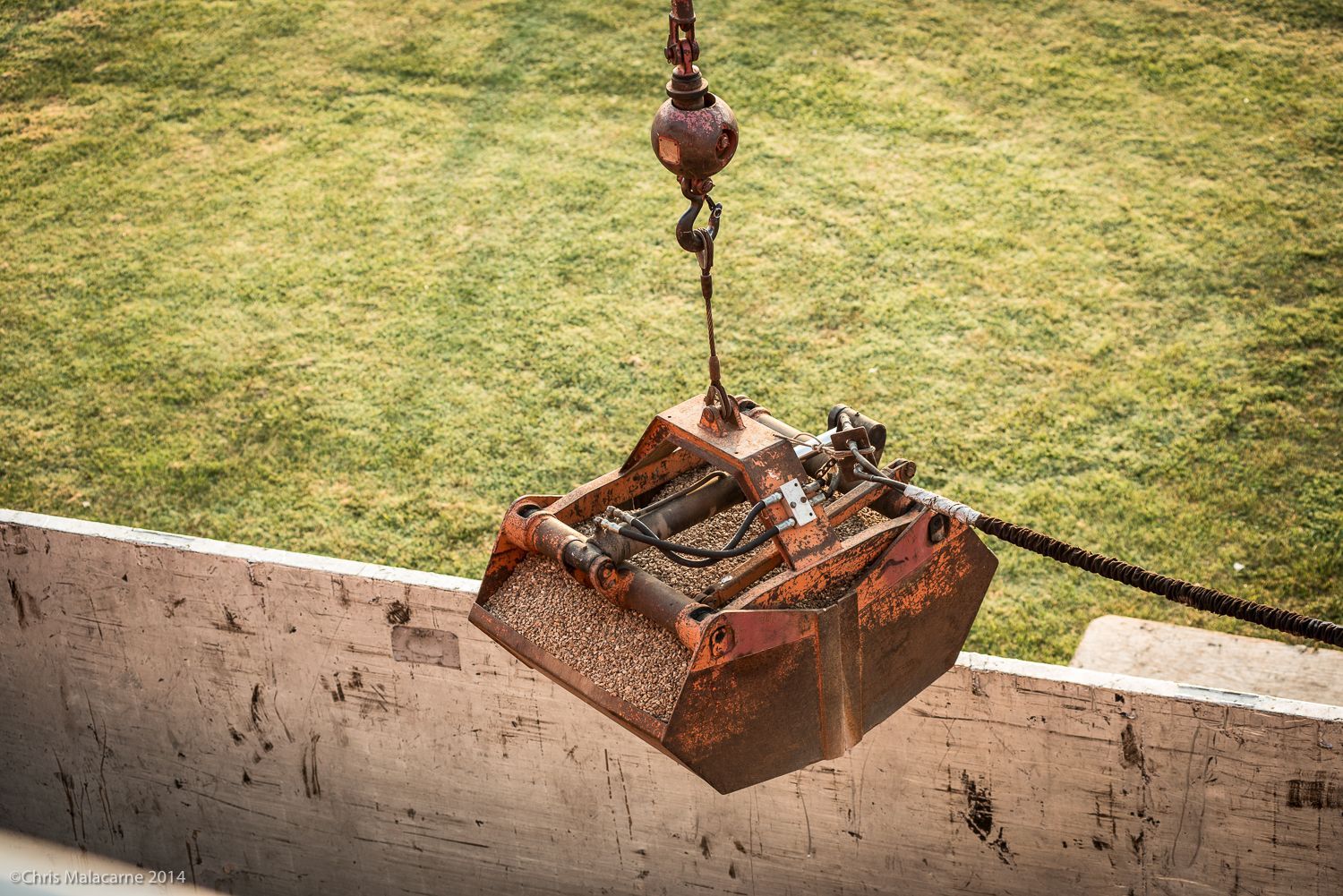 A large metal bucket is hanging from a crane.