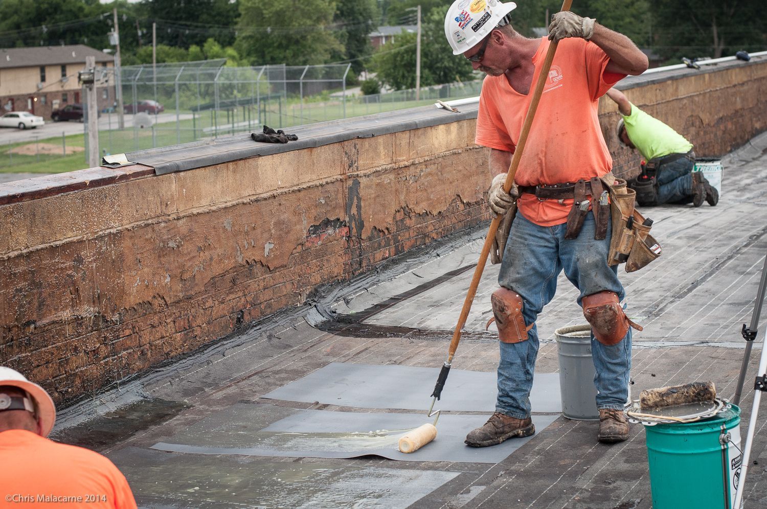 A man is painting a roof with a roller.