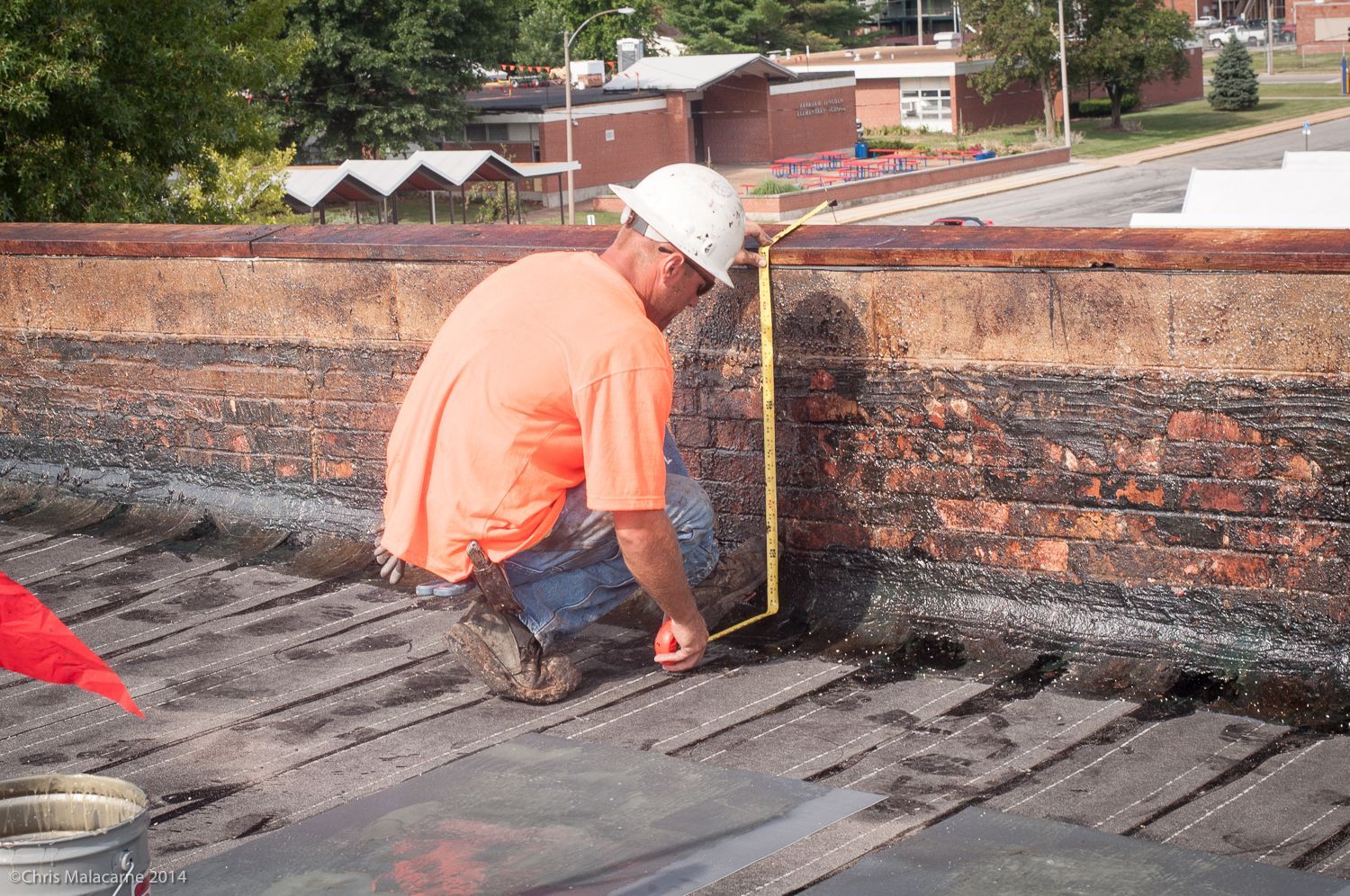 A man is measuring a brick wall with a tape measure.