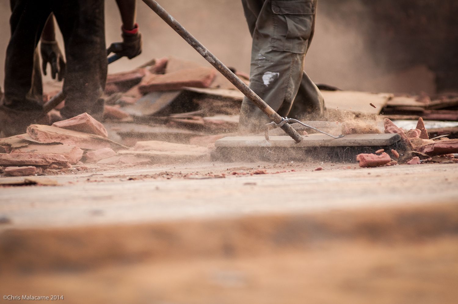 A man is sweeping the ground with a broom.