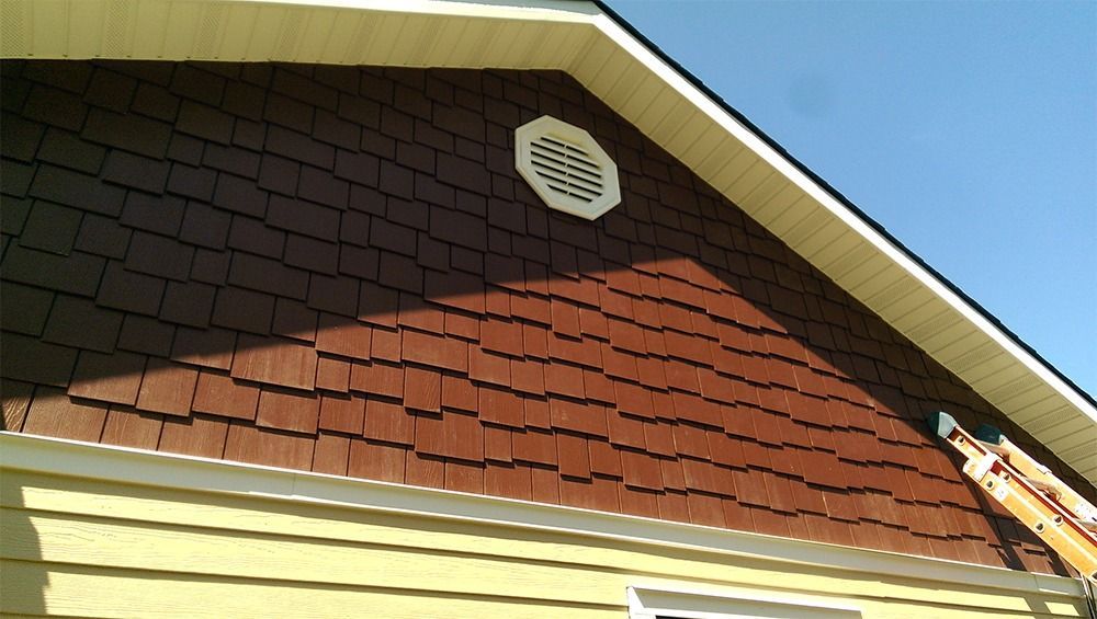 A house with a brown roof and a white vent on the side