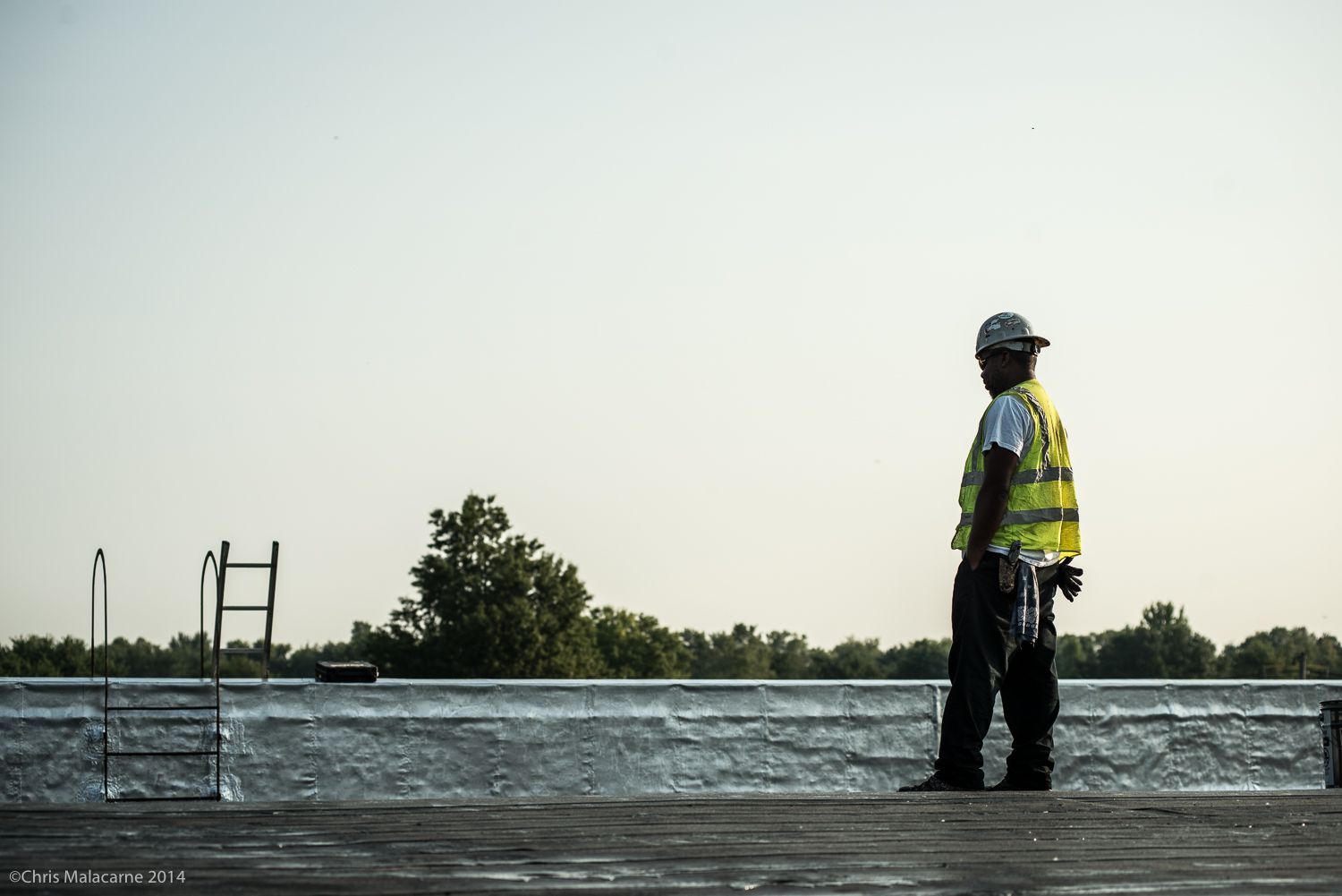 A man in a hard hat is standing on a dock overlooking a body of water.