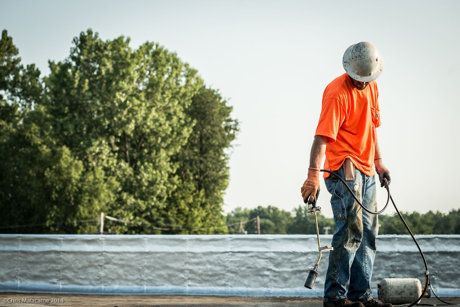 A man is standing on top of a roof holding a torch.