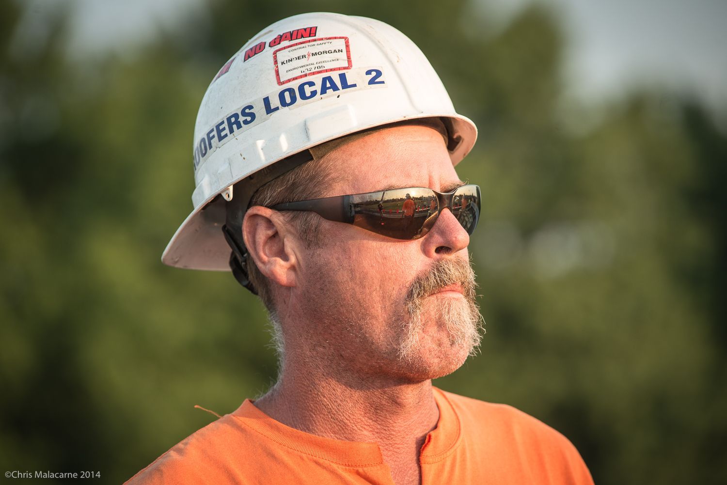 A man wearing a hard hat and sunglasses.