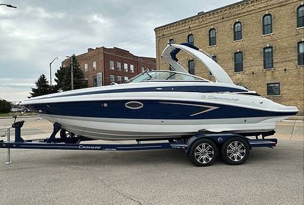 Blue and white boat on a trailer, parked on a street in front of a brick building.