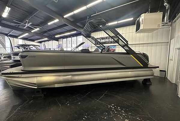 Gray pontoon boat inside a showroom with black canopy and silver pontoons.