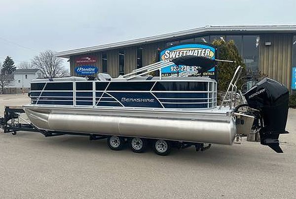Blue and silver Sweetwater pontoon boat on trailer, parked in front of a store.