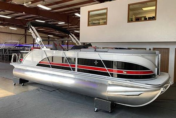 Silver pontoon boat with black and red accents inside a warehouse.