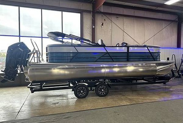 Pontoon boat on trailer, silver and blue with black accents, in a warehouse.