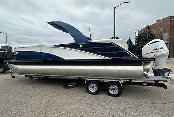 Blue and silver pontoon boat on a trailer, with a Yamaha outboard motor.