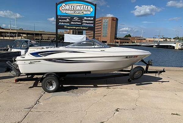 White motorboat on trailer in front of Sweetwater sign and waterfront.