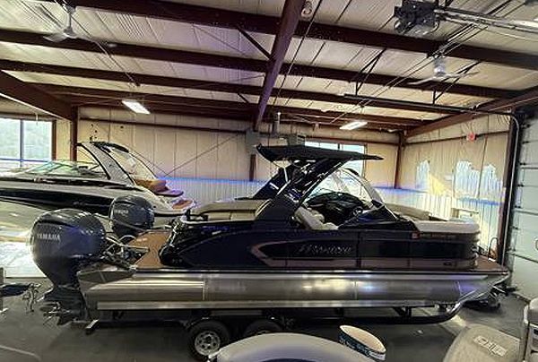 A dark blue pontoon boat with a Yamaha engine in a garage.