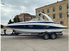 A white and blue motorboat on a trailer, parked on a street in front of a brick building.