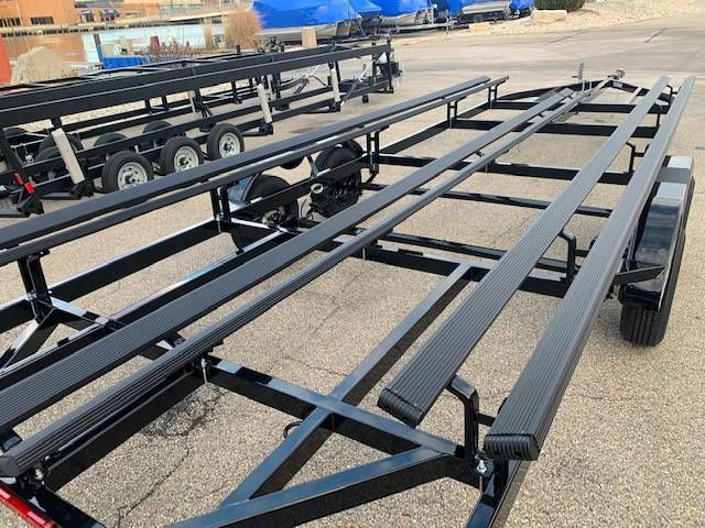 Black boat trailer on pavement, with other trailers in the background.