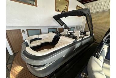 Pontoon boat with white and black seating, black canopy, docked indoors.