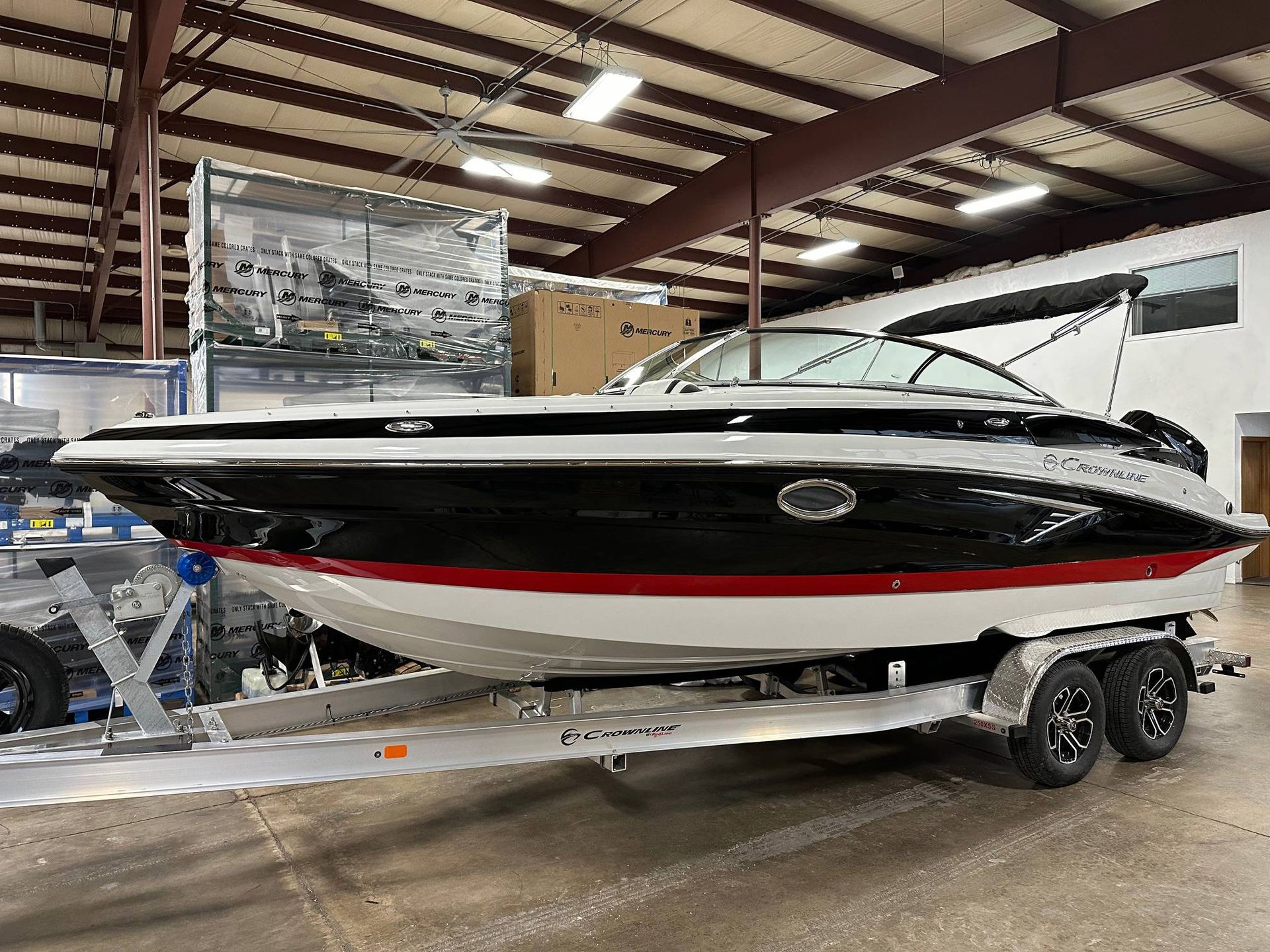 Black and red boat on a trailer in a warehouse. White hull, black trim, and red stripe.