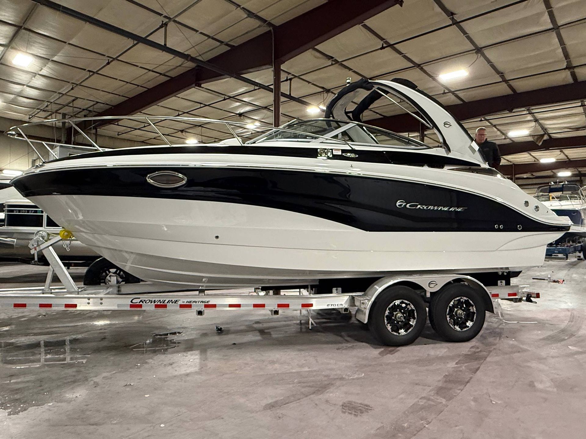 A white and black motorboat on a trailer inside a warehouse.