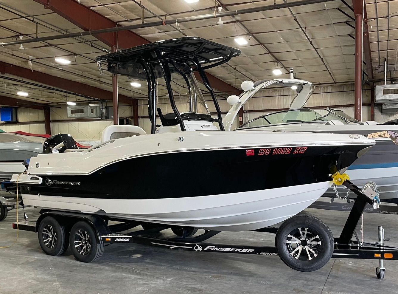 White and black motorboat on a trailer inside a building.