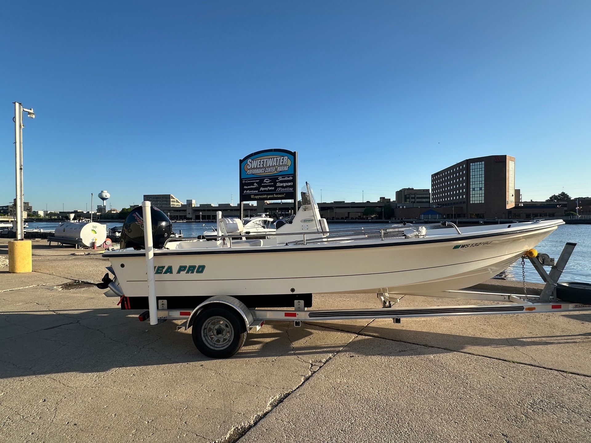 A white Sea Pro boat on a trailer parked at a waterfront dock under a clear, blue sky.