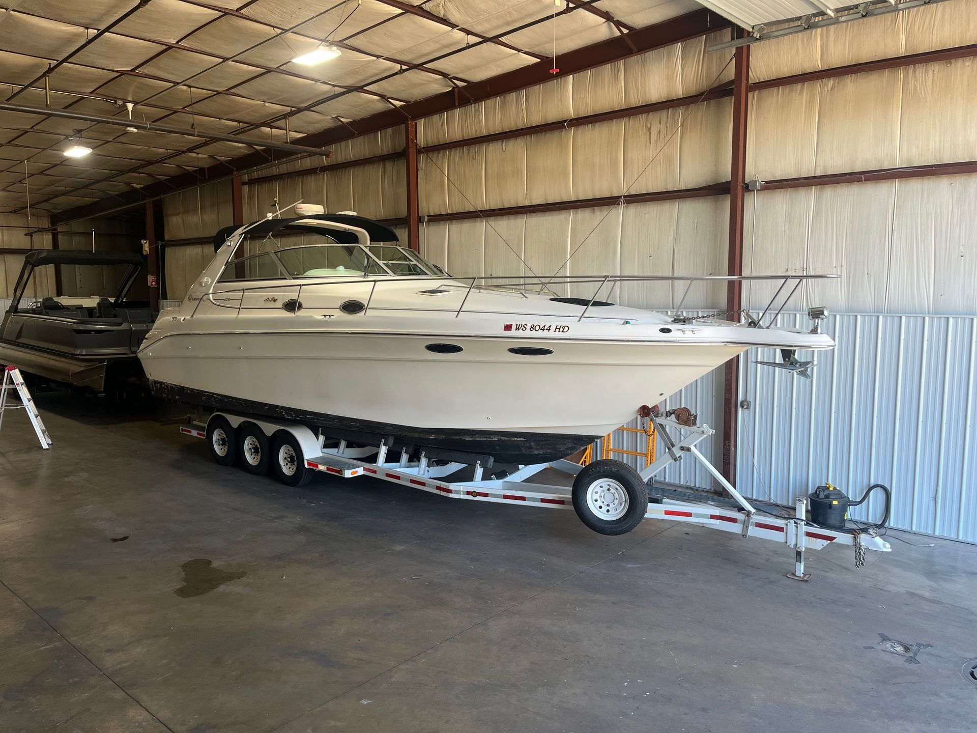 A large white motorboat on a trailer inside a metal building.