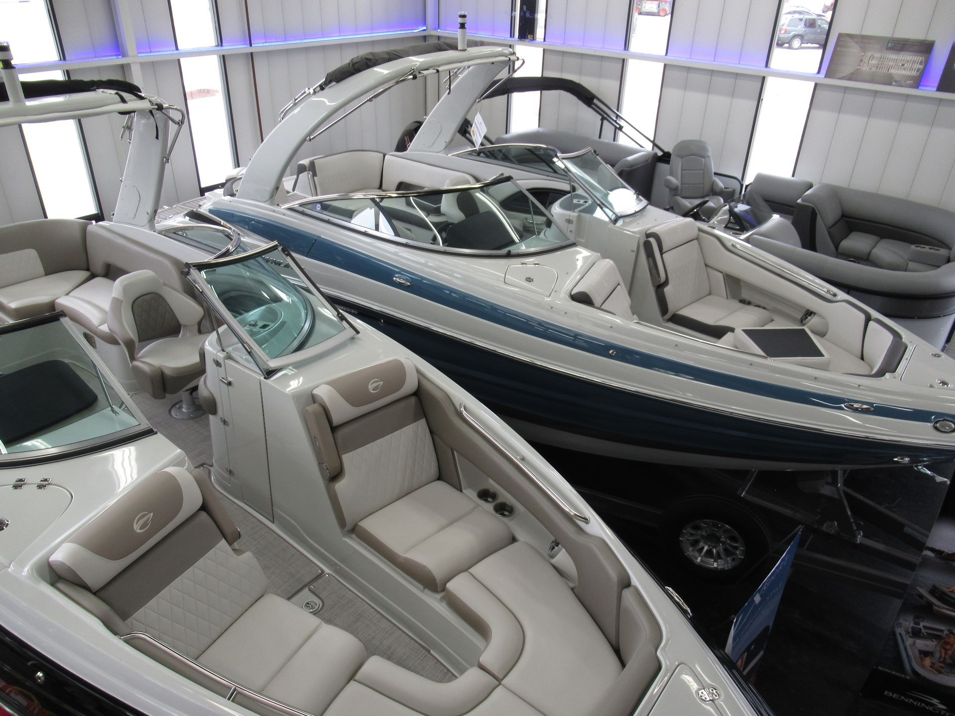 Boats on display indoors, with white, blue, and beige accents, under bright lights.