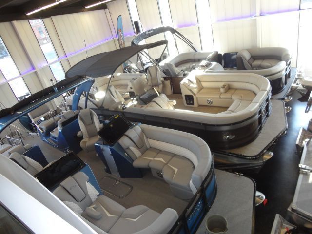 Several new pontoon boats inside a showroom.