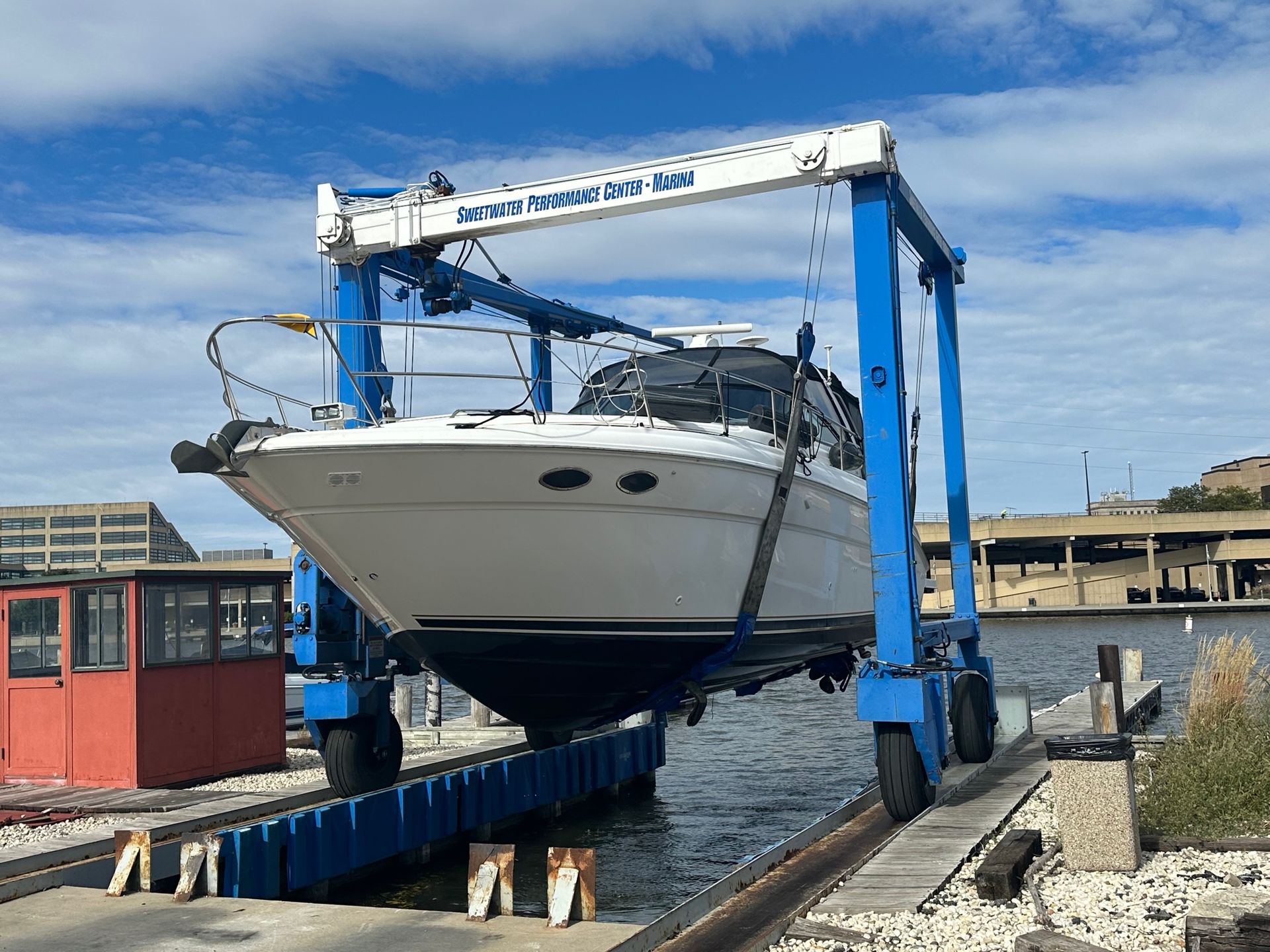 Boat being lifted by a blue marine travel lift in a harbor.